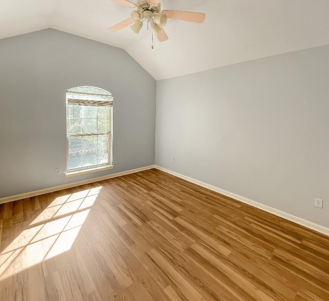 spare room featuring a ceiling fan, lofted ceiling, wood finished floors, and baseboards