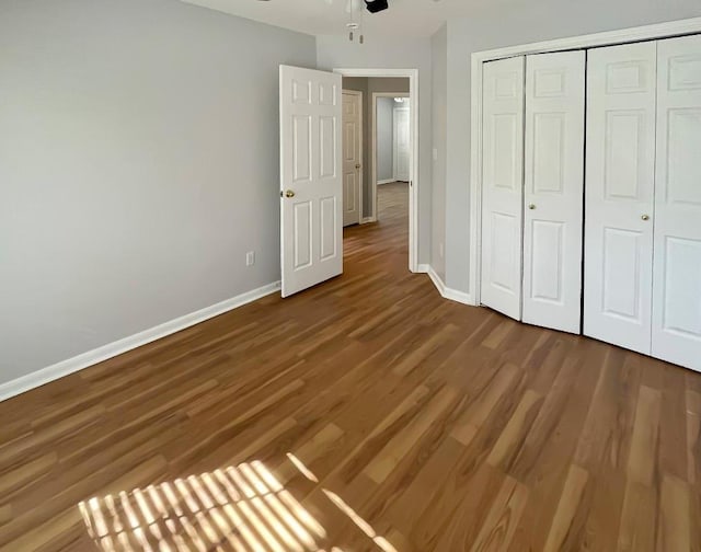 unfurnished bedroom with a closet, baseboards, and wood finished floors