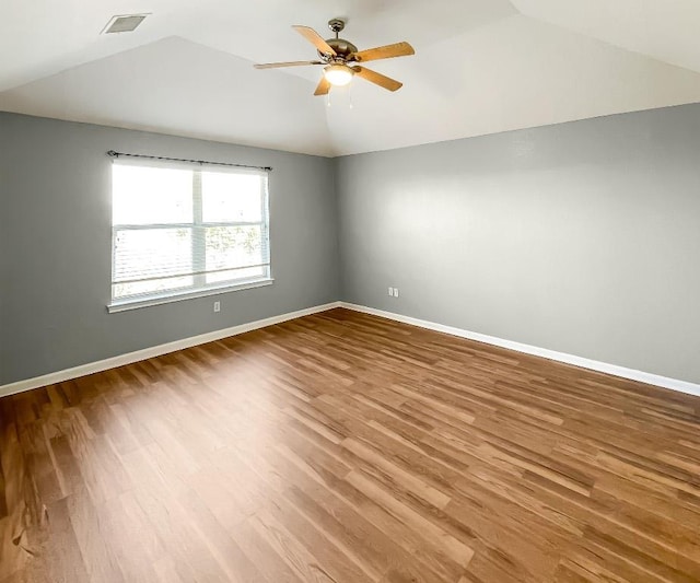 spare room with wood finished floors, baseboards, visible vents, lofted ceiling, and ceiling fan