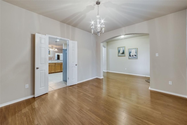 unfurnished room with a chandelier and light wood-type flooring