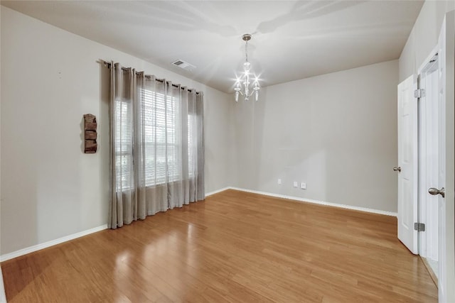 unfurnished room featuring light hardwood / wood-style floors and an inviting chandelier