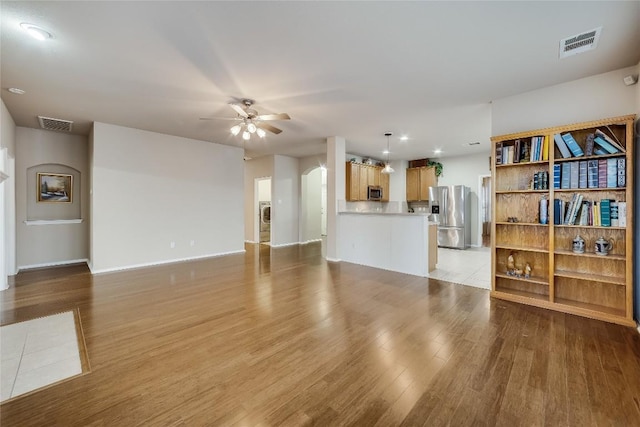 living room with ceiling fan, washer / dryer, and light hardwood / wood-style flooring