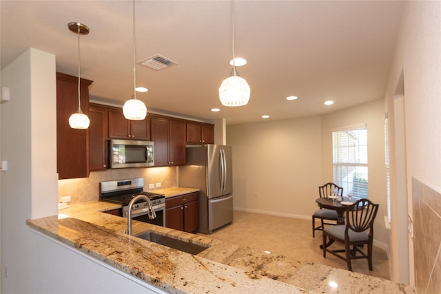 kitchen featuring sink, hanging light fixtures, kitchen peninsula, stainless steel appliances, and light stone countertops