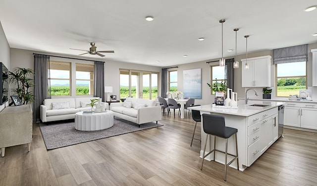 kitchen with sink, ceiling fan, white cabinetry, an island with sink, and decorative light fixtures