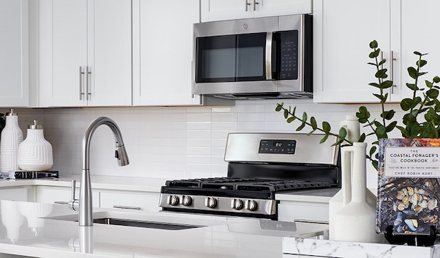 kitchen featuring tasteful backsplash, white cabinetry, and appliances with stainless steel finishes