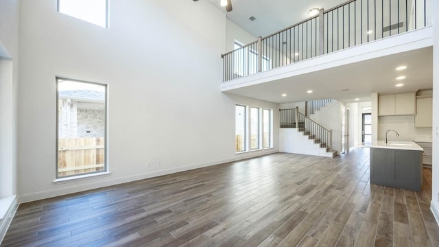 329 Kays Path, Georgetown, TX 78628 - unfurnished living room with a towering ceiling, dark wood-style flooring, a sink, stairs, and baseboards