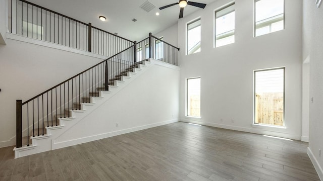 unfurnished living room with a high ceiling, ceiling fan, stairs, plenty of natural light, and recessed lighting