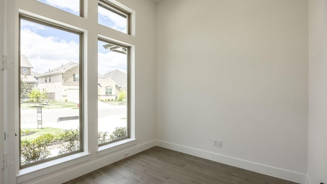 unfurnished room featuring baseboards and dark wood-style floors