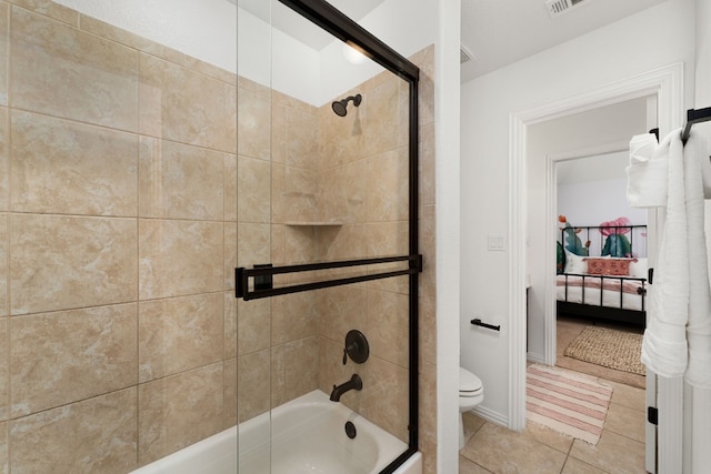 bathroom with tile patterned floors, toilet, and combined bath / shower with glass door