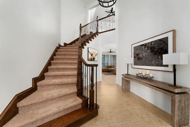 stairway with ceiling fan and a towering ceiling