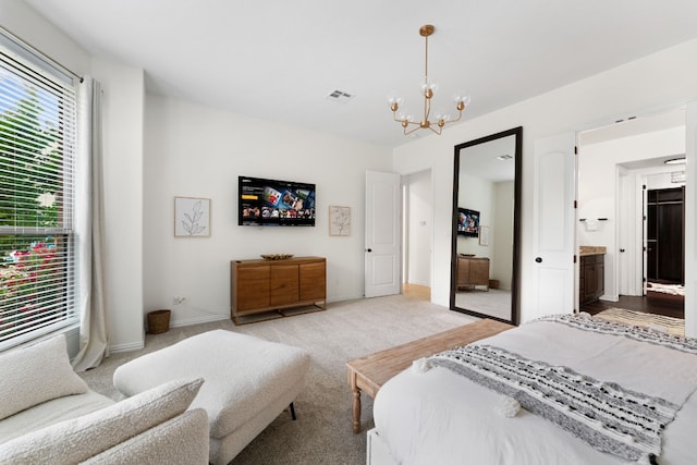 bedroom with ensuite bath, a chandelier, and light carpet