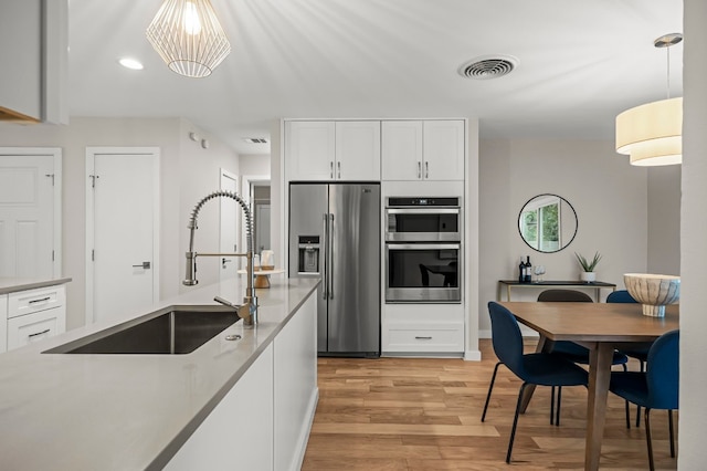 kitchen featuring white cabinets, stainless steel appliances, and decorative light fixtures