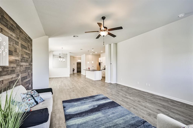 unfurnished living room featuring wood-type flooring and ceiling fan with notable chandelier