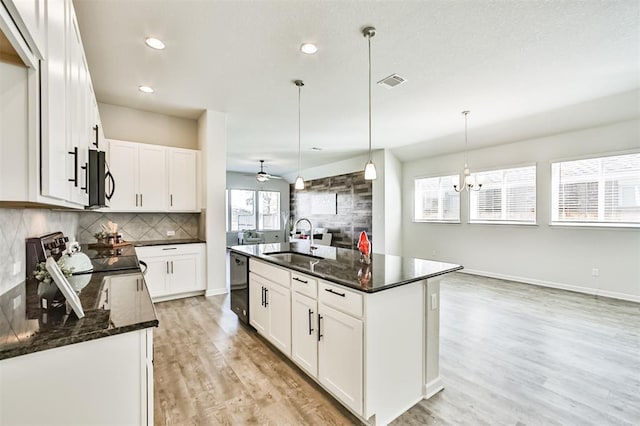 kitchen with white cabinets, hanging light fixtures, a kitchen island with sink, and sink