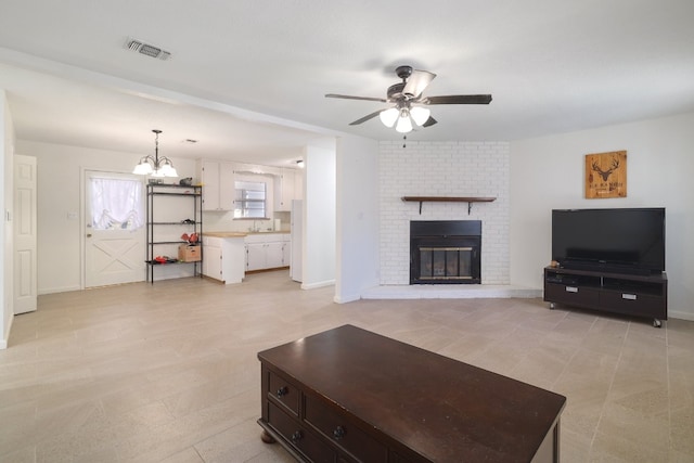 living room featuring a fireplace and ceiling fan with notable chandelier