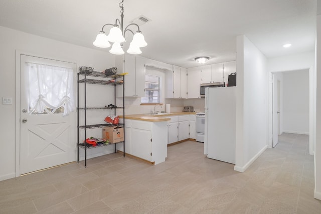 kitchen with stove, white cabinets, decorative light fixtures, and white refrigerator