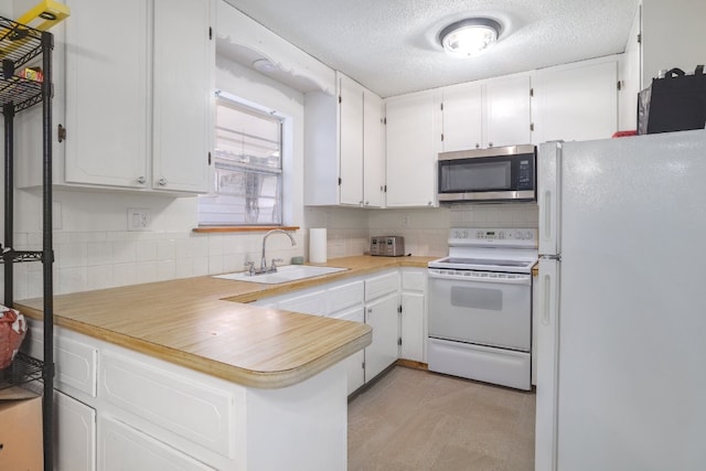 kitchen featuring white cabinetry, sink, kitchen peninsula, a textured ceiling, and white appliances