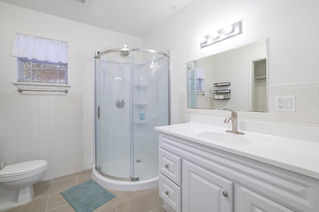 bathroom with tile patterned floors, walk in shower, vanity, tile walls, and toilet