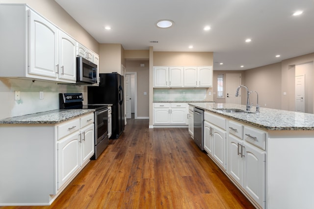 kitchen with stainless steel appliances, white cabinets, sink, and an island with sink