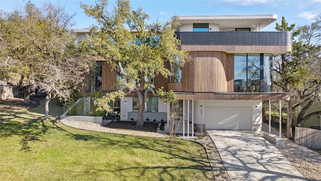 contemporary house with concrete driveway, an attached garage, and a front lawn