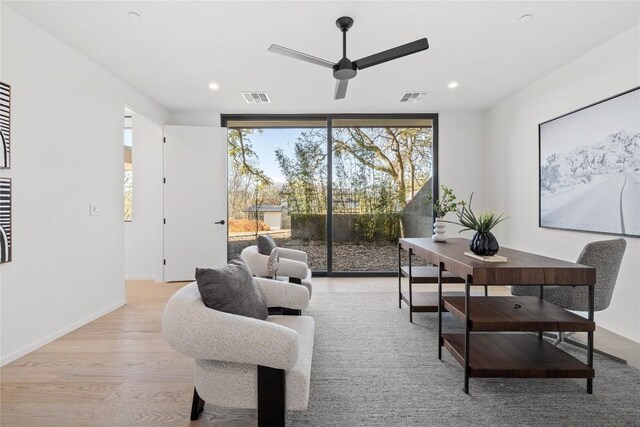 living room with ceiling fan, light wood-type flooring, and expansive windows