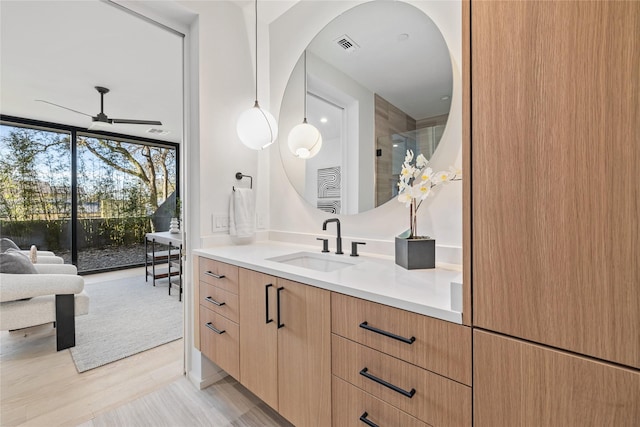 bathroom featuring ceiling fan, a wall of windows, vanity, and hardwood / wood-style flooring