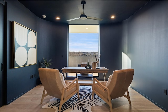 interior space featuring ceiling fan, a wall of windows, and light hardwood / wood-style flooring