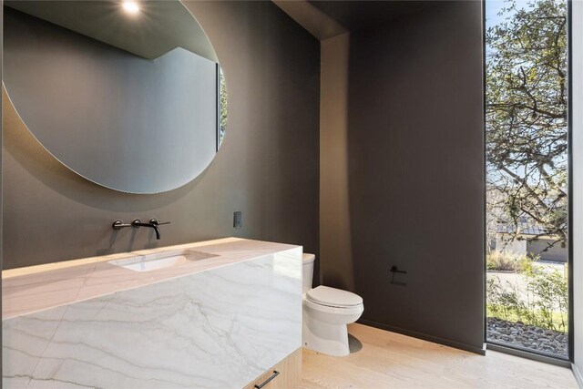 bathroom featuring vanity, a wealth of natural light, hardwood / wood-style flooring, and toilet