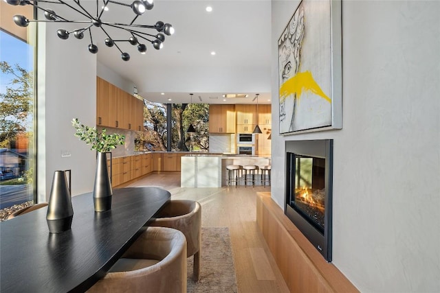 dining space featuring light wood-type flooring, plenty of natural light, and a glass covered fireplace