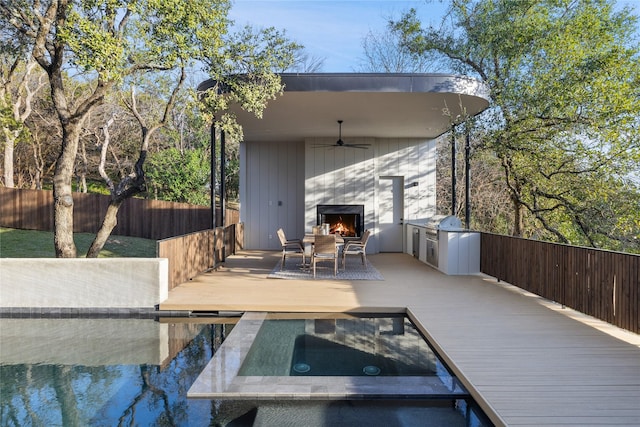 deck featuring an in ground hot tub, ceiling fan, area for grilling, and fence