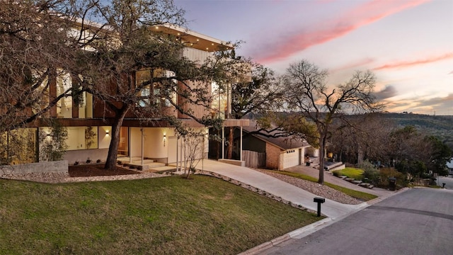 view of front of house featuring an attached garage, concrete driveway, and a yard