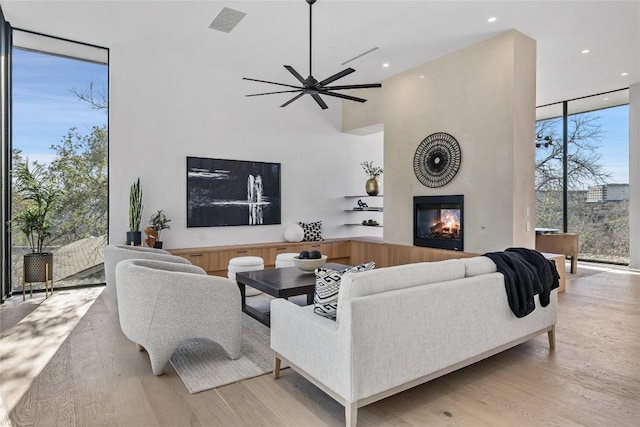 living area featuring visible vents, floor to ceiling windows, wood finished floors, and a glass covered fireplace