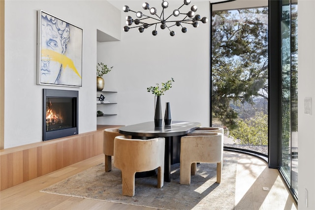 dining room featuring light wood-type flooring, wood walls, and a chandelier