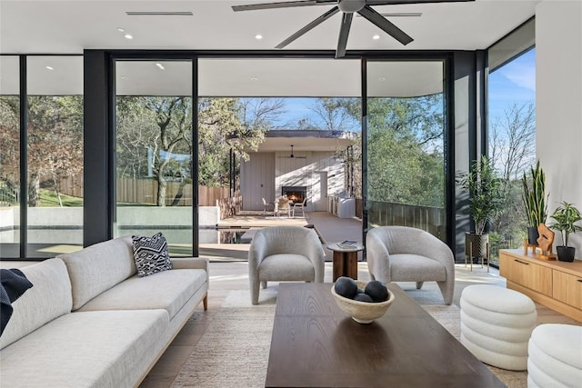 sunroom featuring ceiling fan and a lit fireplace