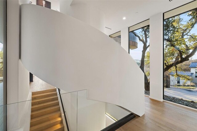 stairs featuring a wall of windows and wood-type flooring