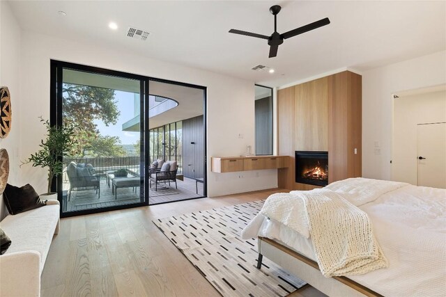 bedroom featuring a fireplace, ceiling fan, access to outside, and light hardwood / wood-style flooring