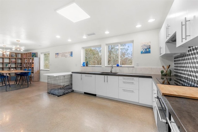 kitchen with black electric stovetop, white cabinetry, and kitchen peninsula