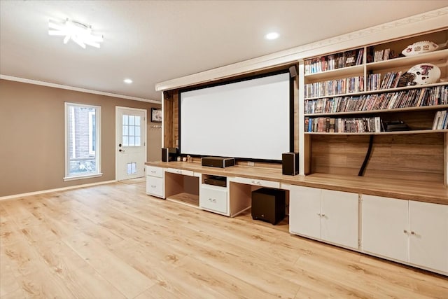 home theater with crown molding, light hardwood / wood-style flooring, and built in desk