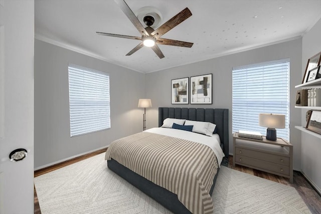 bedroom featuring hardwood / wood-style flooring, ceiling fan, ornamental molding, and multiple windows