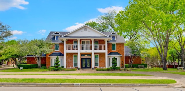 view of front of home featuring a front lawn, a balcony, and french doors