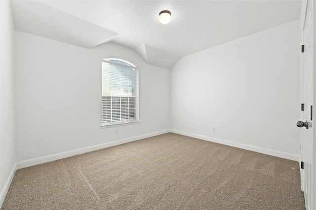 carpeted empty room with vaulted ceiling