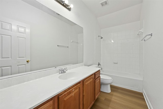 full bathroom with hardwood / wood-style flooring, tiled shower / bath, vanity, and toilet