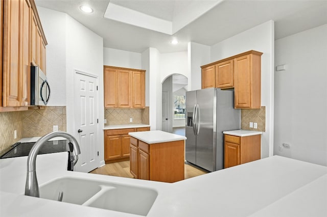 kitchen featuring sink, decorative backsplash, appliances with stainless steel finishes, and a kitchen island