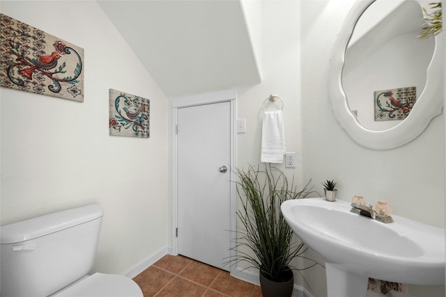 bathroom featuring tile patterned flooring, sink, vaulted ceiling, and toilet