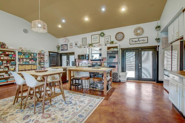 dining room featuring concrete flooring, sink, high vaulted ceiling, and french doors