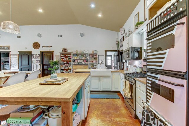 kitchen with stainless steel appliances, wooden counters, kitchen peninsula, pendant lighting, and white cabinets