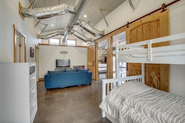 bedroom featuring a towering ceiling and a barn door