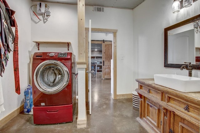 clothes washing area featuring a barn door, washer / clothes dryer, and sink