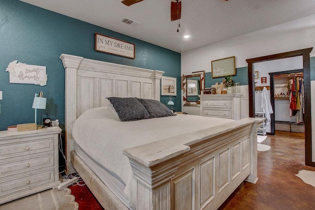bedroom featuring a ceiling fan, a textured wall, finished concrete floors, and visible vents