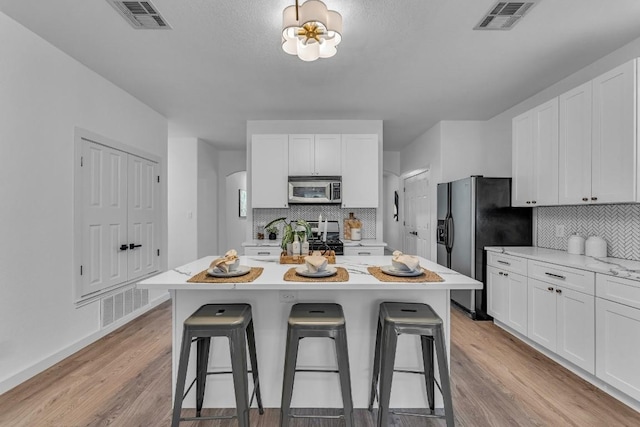 kitchen featuring white cabinets, a breakfast bar, a kitchen island, and appliances with stainless steel finishes